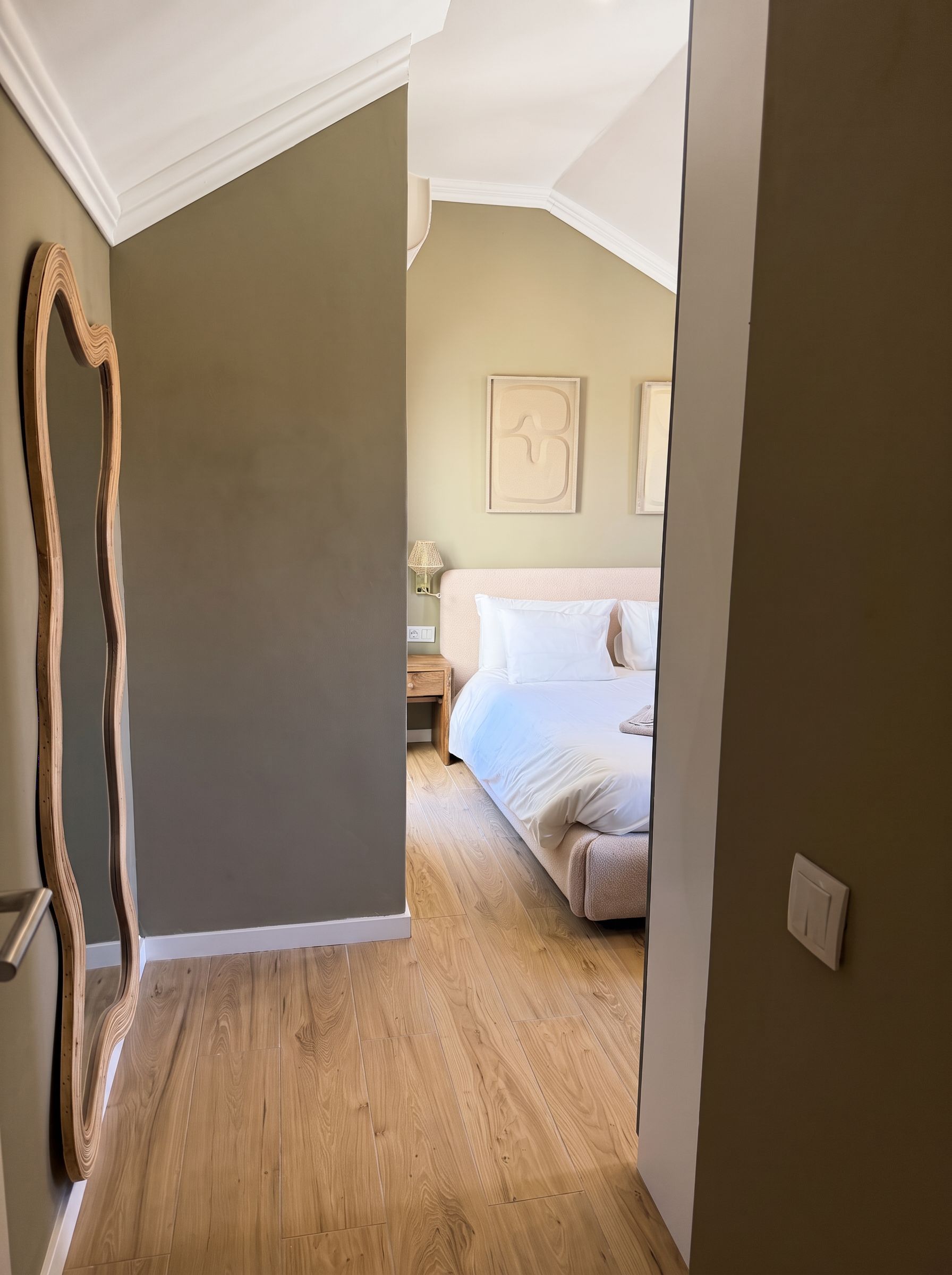 A bedroom with a bed, a nightstand, and a wall-mounted lamp.