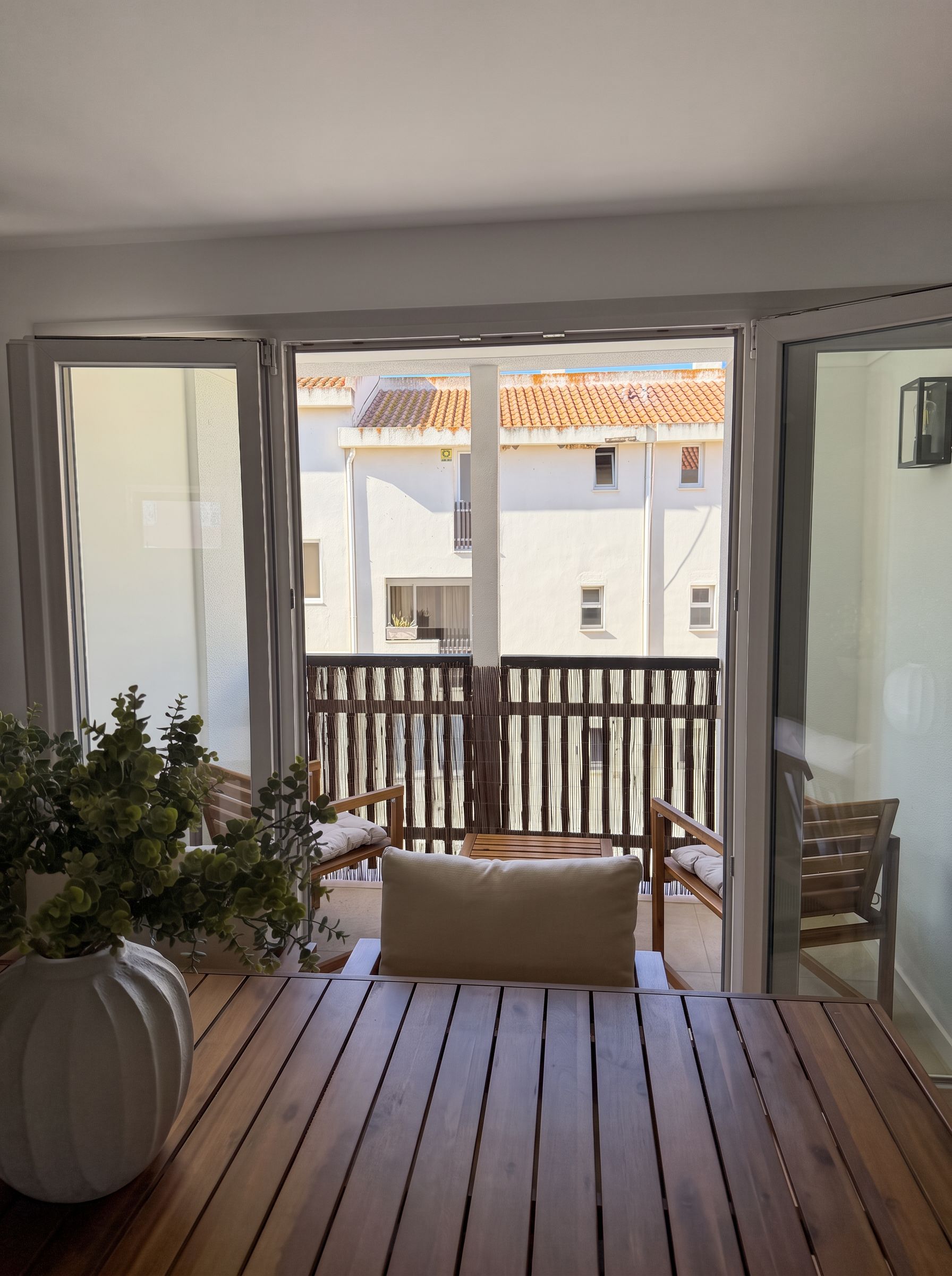 A balcony with a wooden floor, a bench, and a potted plant.