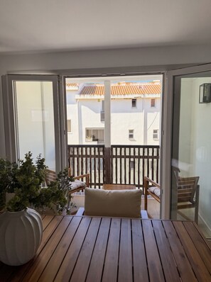 Un balcon avec un plancher en bois, un banc et un pot de fleurs.
