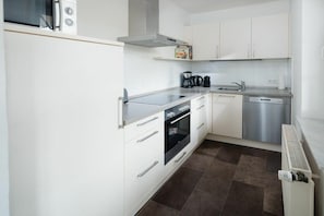 Eine moderne Küche mit weißen Schränken, einem Edelstahl-Geschirrspüler und einem eingebauten Backofen.