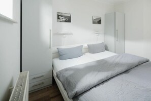 Ein Schlafzimmer mit einem Bett, zwei Nachttischen, einem Kleiderschrank und zwei Wandleuchten.