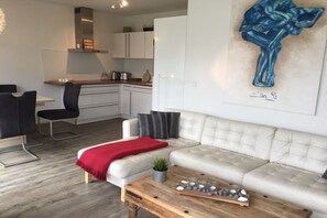 A modern living room with a sofa, a coffee table, and a painting on the wall. - Holiday apartment with 2 bedrooms (Scharbeutz)