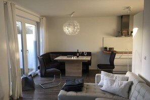 Een moderne woonkamer met een bank, een eettafel en een kroonluchter.