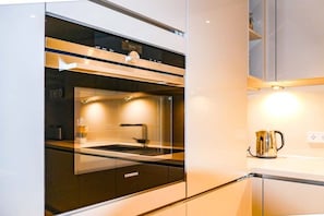 A modern kitchen with a built-in oven, a coffee maker, and a visible clock. - Holiday apartment with 2 bedrooms (Timmendorfer Strand)