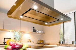 A modern kitchen with a stainless steel range hood, a fruit bowl on the counter, and a 'HOME' sign above the cabinets. - Holiday apartment with 2 bedrooms (Timmendorfer Strand)