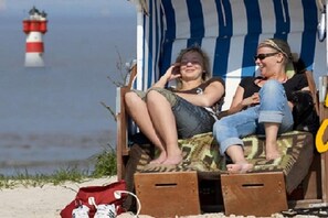 Een strandstoel met uitzicht op de zee en een vuurtoren in de verte.
