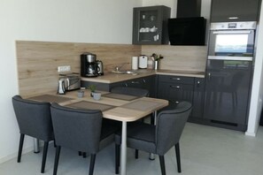 Una cocina compacta con una mesa de comedor, sillas, cafetera y refrigerador.