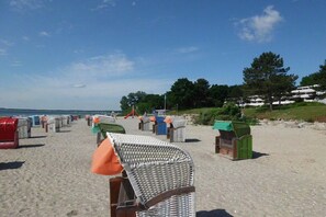 Ein Strand mit Reihen von Liegestühlen und Sonnenschirmen, ein klarer Himmel und ein weiter Blick auf das Meer.