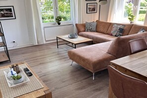 Ein modernes Wohnzimmer mit einer Couch, einem Couchtisch und Blick auf Grünfläche.