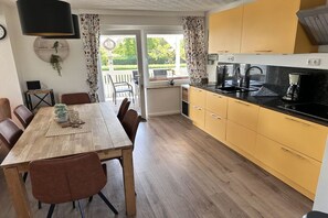 Eine moderne Küche mit Holzschränken, einem Esstisch mit Stühlen und Blick ins Freie.