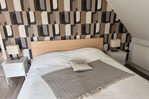 Ein Schlafzimmer im modernen Stil, mit einem Bett, einem Kopfteil, zwei Nachttischen mit Lampen und einer Wand mit Muster.