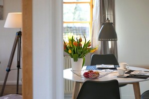 A dining area with a round table, a flower vase, and a lamp. - Holiday apartment with 1 bedroom (Gelting)