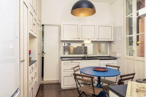 A compact kitchen with white cabinets, a sink, and a round table with chairs. - Bernini in Cavour (Roma)