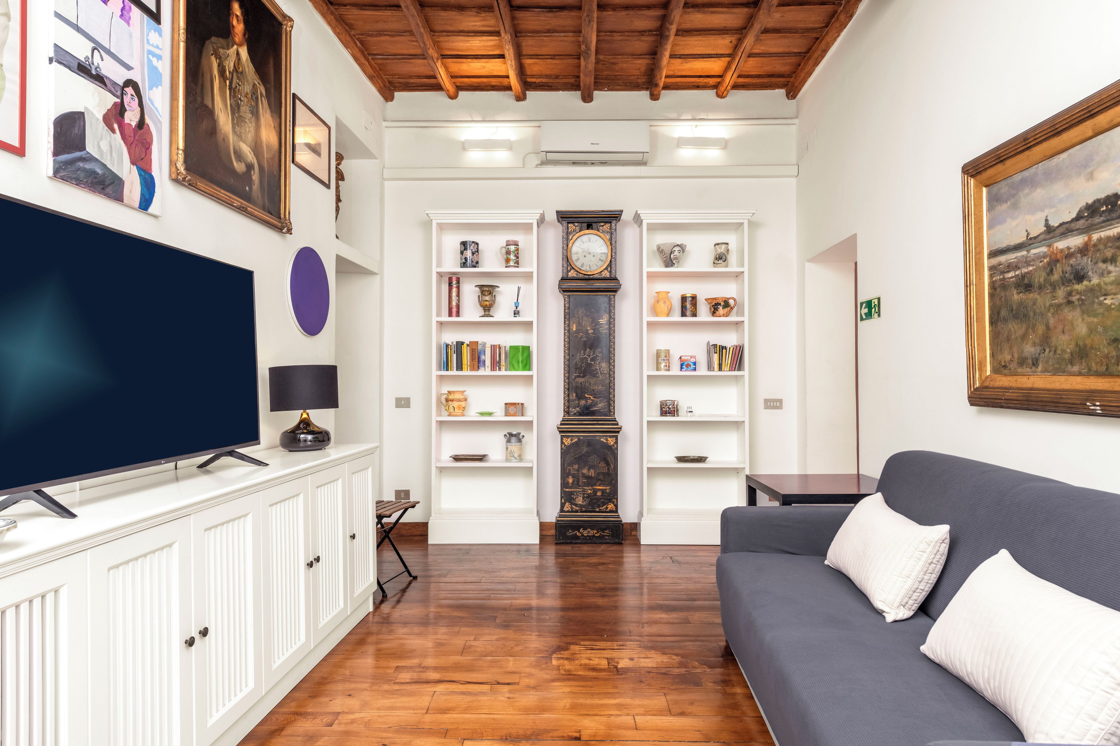 A living room with a television, bookshelves, a sofa, and a painting.
