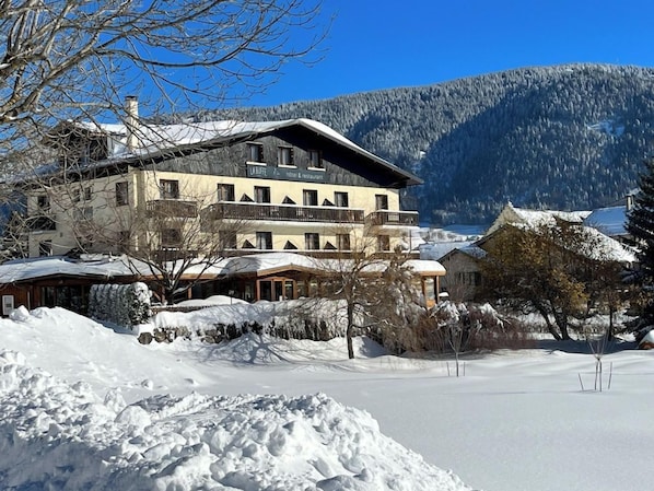 A hotel with a traditional Alpine architectural style, featuring a large building with multiple windows and balconies, situated in a snowy mountainous area. - Hôtel Restaurant De La Buffe (Autrans-Meaudre-en-Vercors)