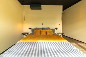 Un llit amb un estovat a ratlles, un capçal i dues taules de nit.
