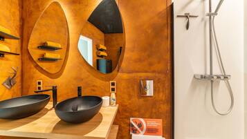 Casa de banho com design moderno, apresentando um espelho grande, duas bacias pretas, chuveiro e aviso de 'Não Despejar Nada'.