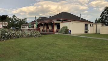 A two-story building with a covered porch and a small garden area.