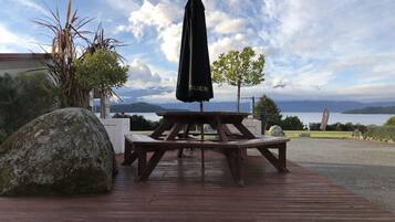 A wooden deck with a picnic table and a black umbrella.