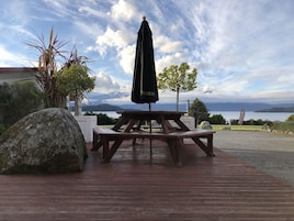 Una terraza de madera con una mesa de picnic y un paraguas negro.