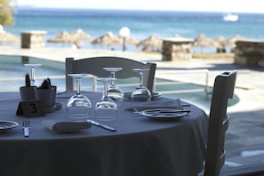 Mesa lista para comer con vista al mar, tarjetas de lugar numeradas y cielo despejado.
