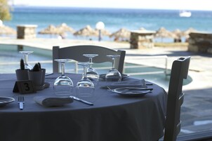 Mesa lista para comer con vista al mar, tarjetas de lugar numeradas y cielo despejado.