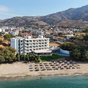 A coastal hotel with multiple floors, a pool, and a beach with umbrellas. - Apollon Suite (Karystos)