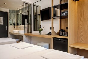 A modern hotel room with a large bed, a small desk, a television, and a bathroom with a mirror and sink. - Canadian Annex (Zakynthos)