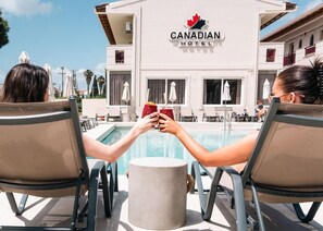 Un hotel canadiense con zona de piscina, sillas de descanso y sombrillas.