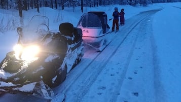 Un vehículo de nieve en un camino cubierto de nieve, con huellas que se alejan.