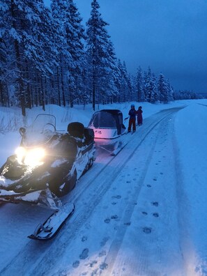Ein Schneemobil auf einer verschneiten Straße, Fußspuren ziehen sich davon.