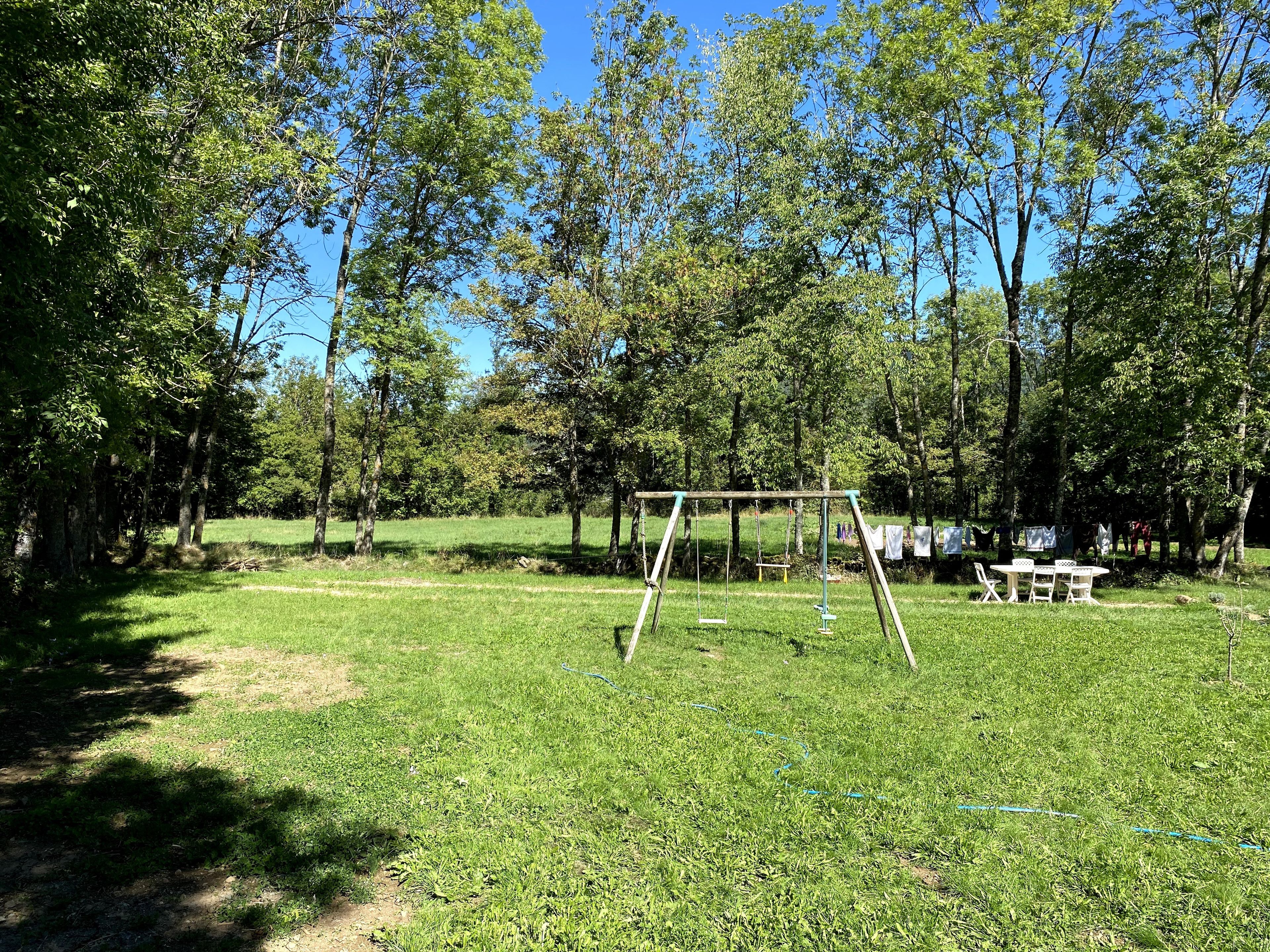Un espace vert avec des balançoires et des tables de pique-nique.