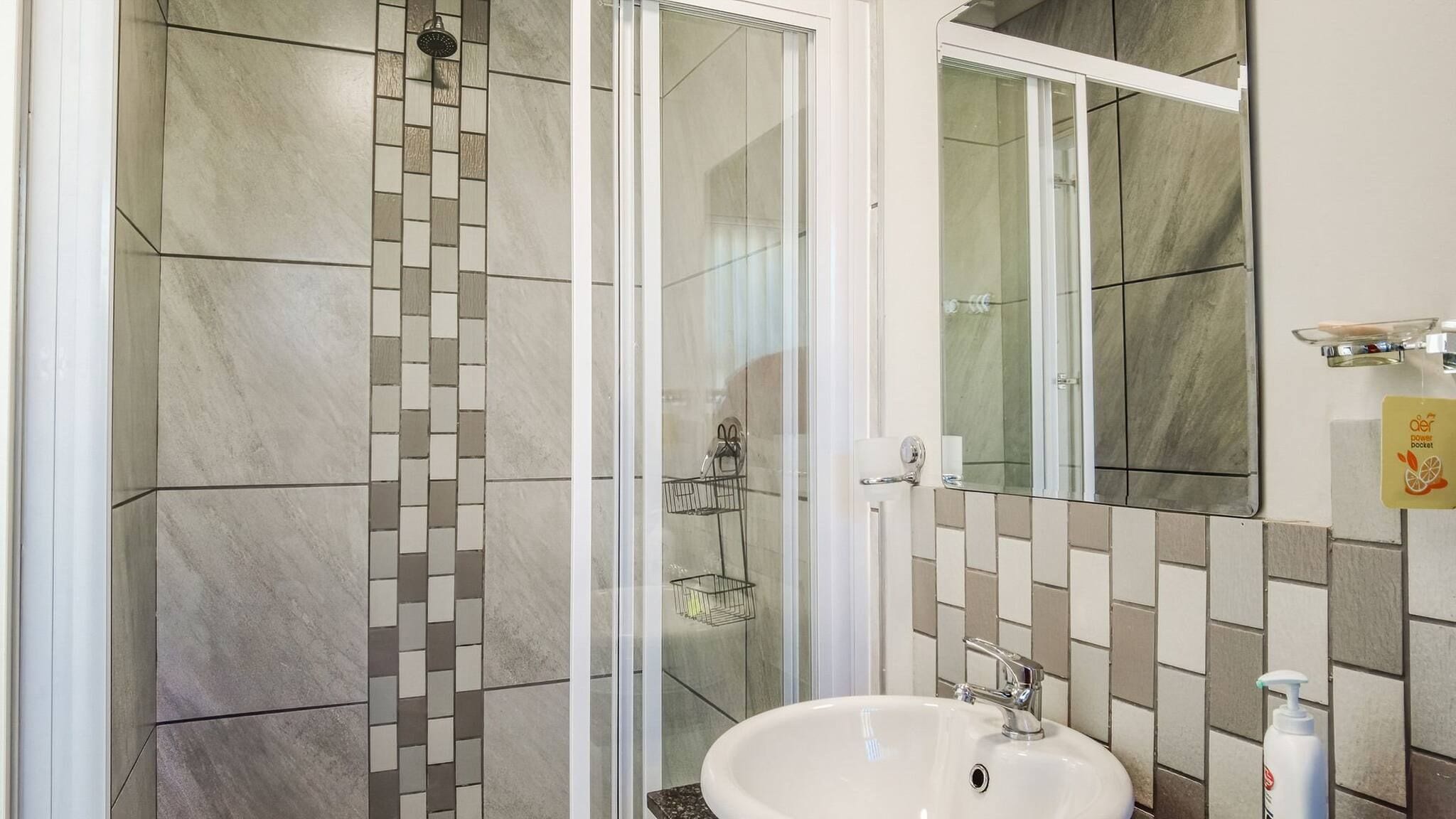 A bathroom with a shower, a sink, and a mirror.