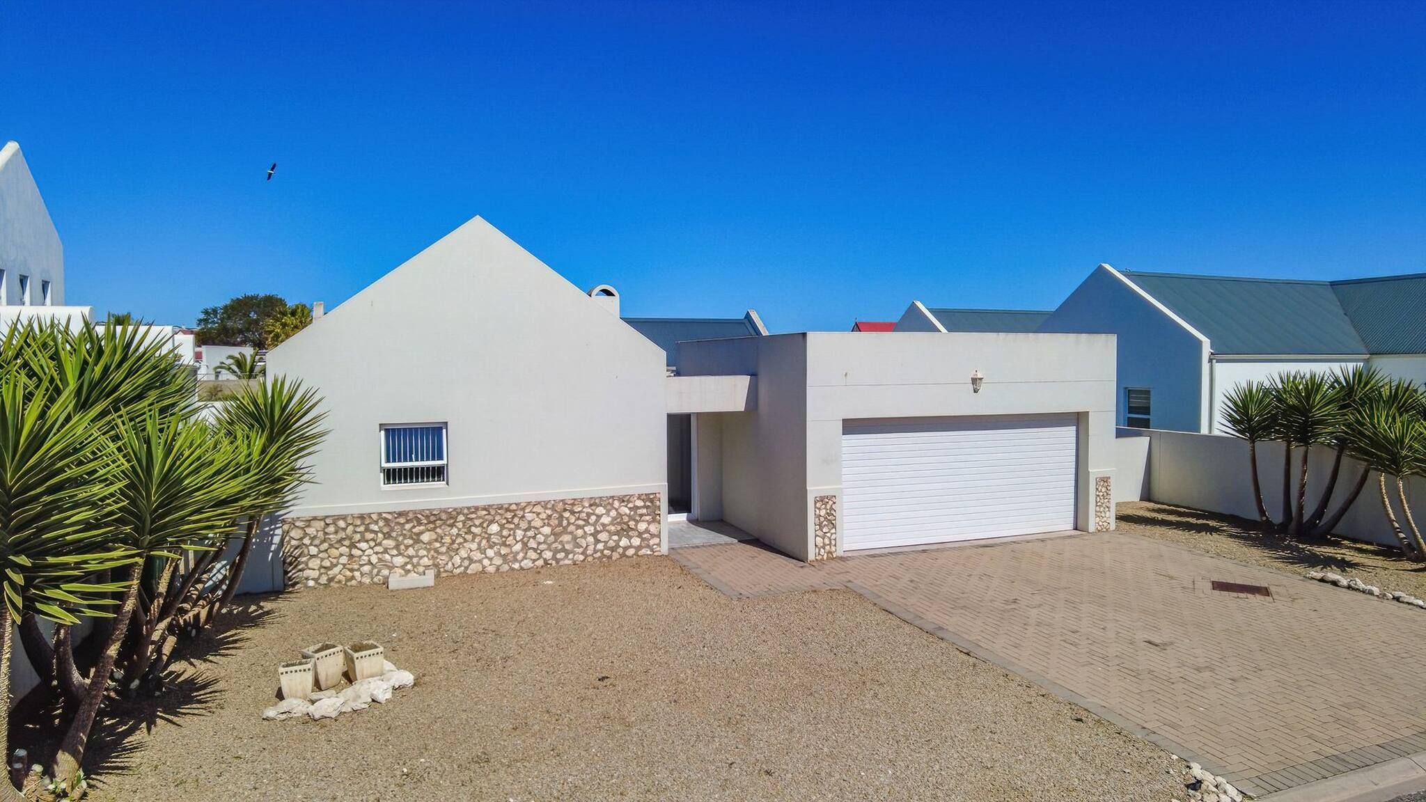 A modern two-story house with a garage, a stone foundation, and a paved driveway.