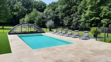 A swimming pool with a sunshade structure and lounge chairs.