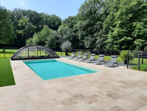 Una piscina con una estructura de sombrilla y sillas de descanso.