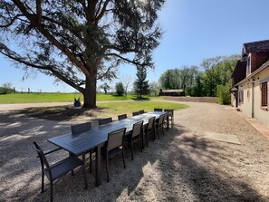 An outdoor dining area with a table and chairs, a large tree, and a building in the background. - Holiday Home 'Gîte De La Boivinière' with Private Pool, Private Terrace and Wi-Fi (Autrèche)