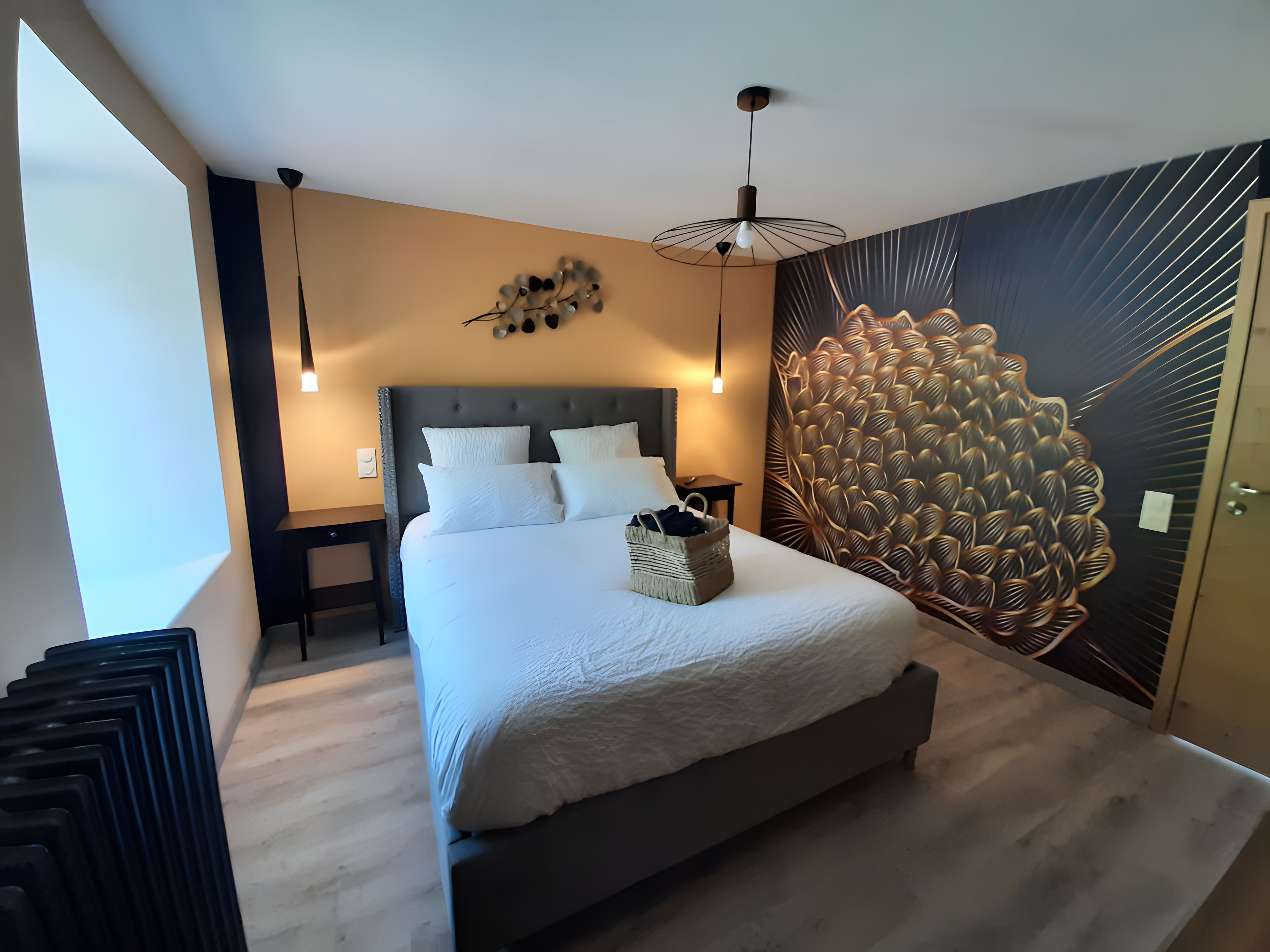 Un dormitorio moderno con una cama grande, una obra de arte en la pared y una lámpara de techo.