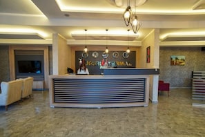 A reception desk with a modern design, a television, and a clock on the wall. - Ugurlu Termal Resort (Gaziantep)