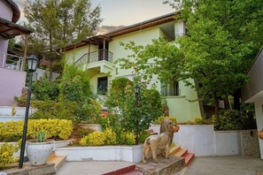 A building with a balcony, surrounded by greenery and a dog statue. - Ugurlu Termal Resort (Gaziantep)
