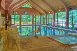 Una piscina interior con vigas de madera y ventanas amplias.