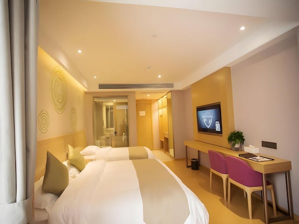 A hotel room with two beds, a desk, a chair, a television, and a mirror.