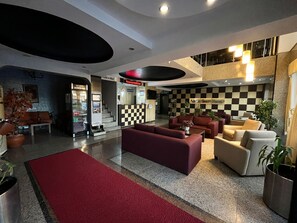 A hotel lobby with a reception desk, seating area, and a cafe. - GRAND GEBZE HOTEL (Gebze)