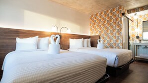 A hotel room with two beds, a wooden headboard, a patterned wall, and a small bathroom area. - Hotel Tucson Downtown (Tucson)