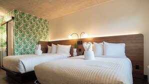 Een hotelkamer met twee bedden, een behang met patroon en een houten hoofdeinde.