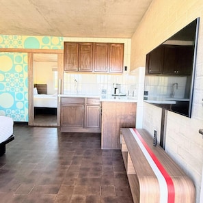 A compact kitchen with wooden cabinets, a built-in microwave, and a bench. - Hotel Tucson Downtown (Tucson)