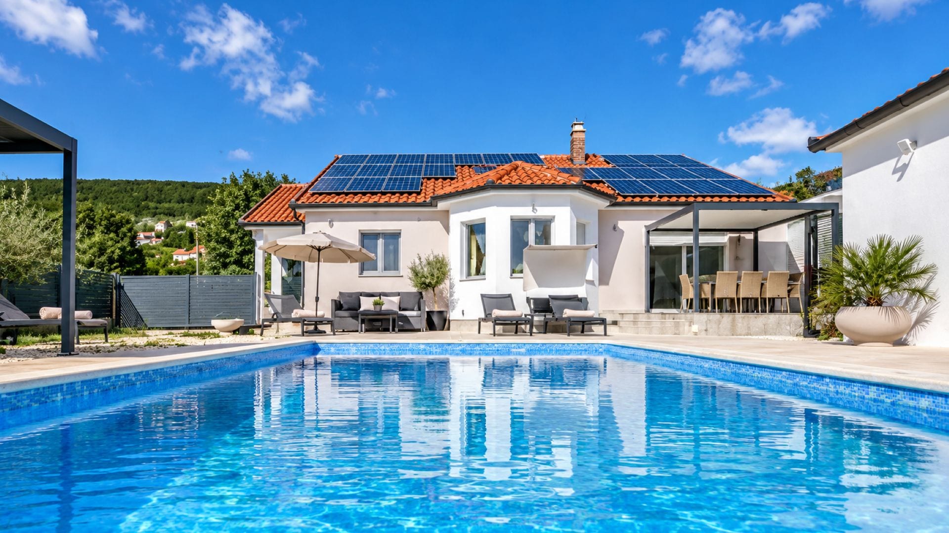 A modern house with a swimming pool, solar panels, and outdoor furniture.