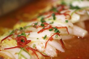 A close-up of a dish with sliced fish, green onions, and red chili slices. - Lavande Hotel (Guiyang)