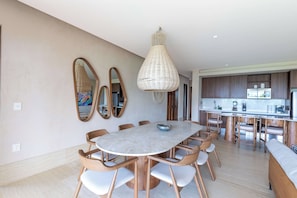 A modern kitchen with a central island, wooden chairs, and a hanging light fixture. - Artila Isla Mujeres: Luxury Beachfront Residence in Isla Mujeres (Isla Mujeres)