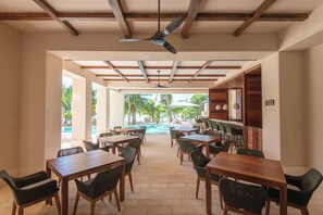 A restaurant with outdoor seating, a pool, and wooden beams on the ceiling. - Artila Isla Mujeres: Luxury Beachfront Residence in Isla Mujeres (Isla Mujeres)